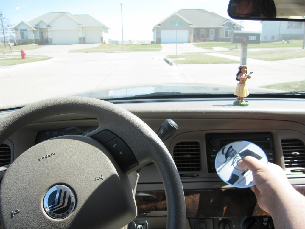 Photograph of the dashboard of a car with a hulu girl and a Frank Sinatra CD.